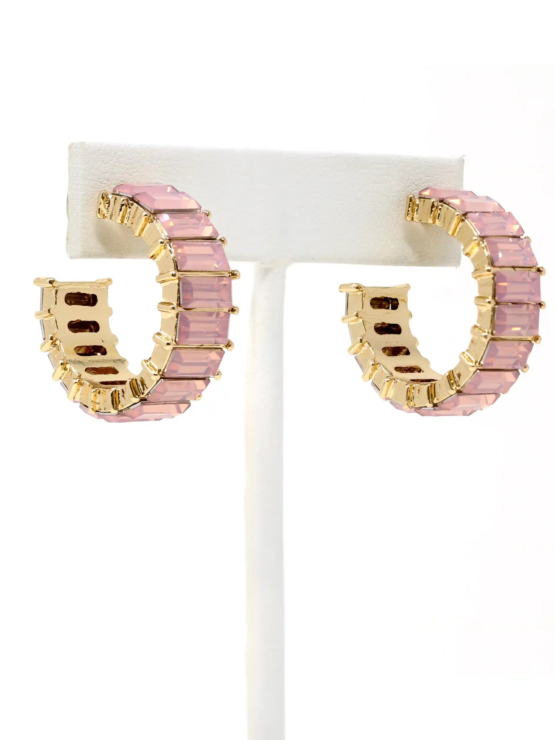 Pink hoop earrings with gold accents on a white stand