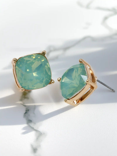 Pair of earrings with mint opal and gold accents on a light background