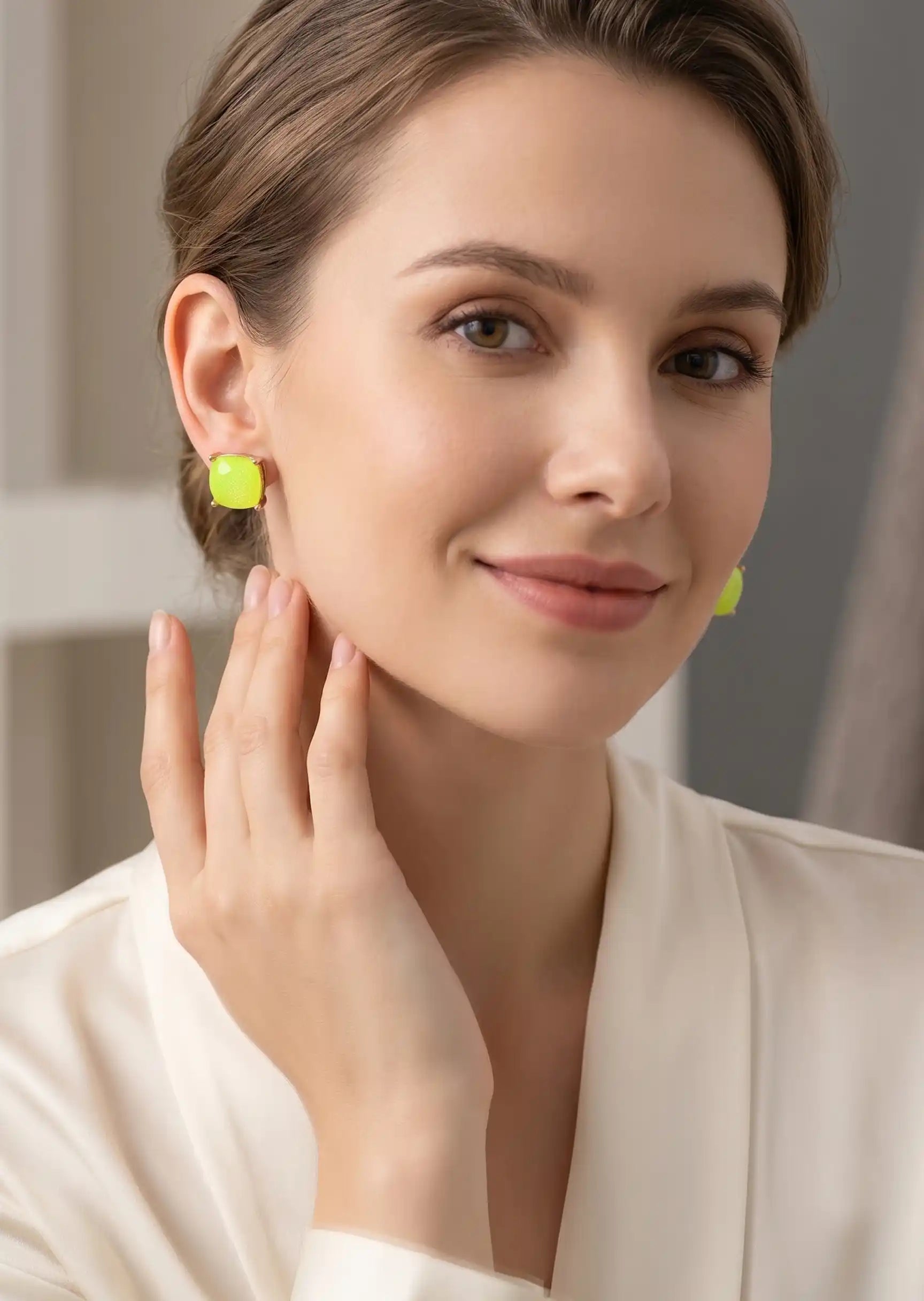 Woman wearing green earrings with a neutral background