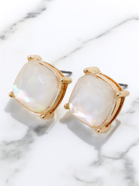 Gold-framed earrings with white stones on a marble surface