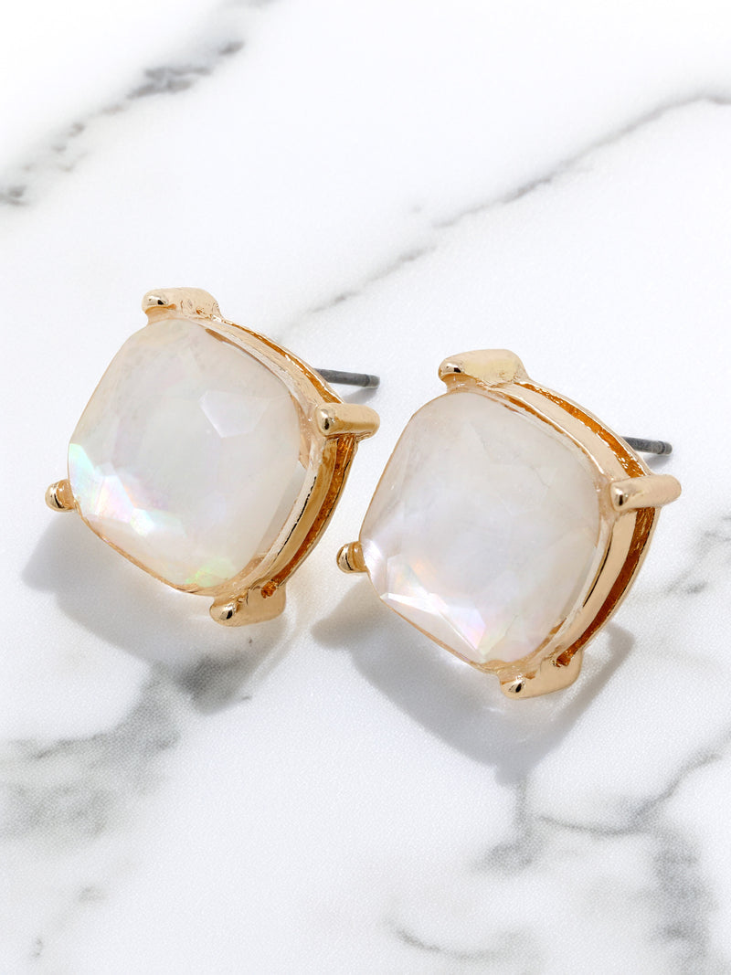 Gold-framed earrings with white stones on a marble surface