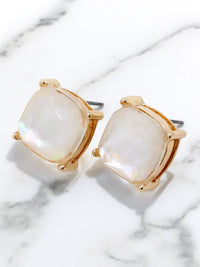Gold-framed earrings with white stones on a marble surface