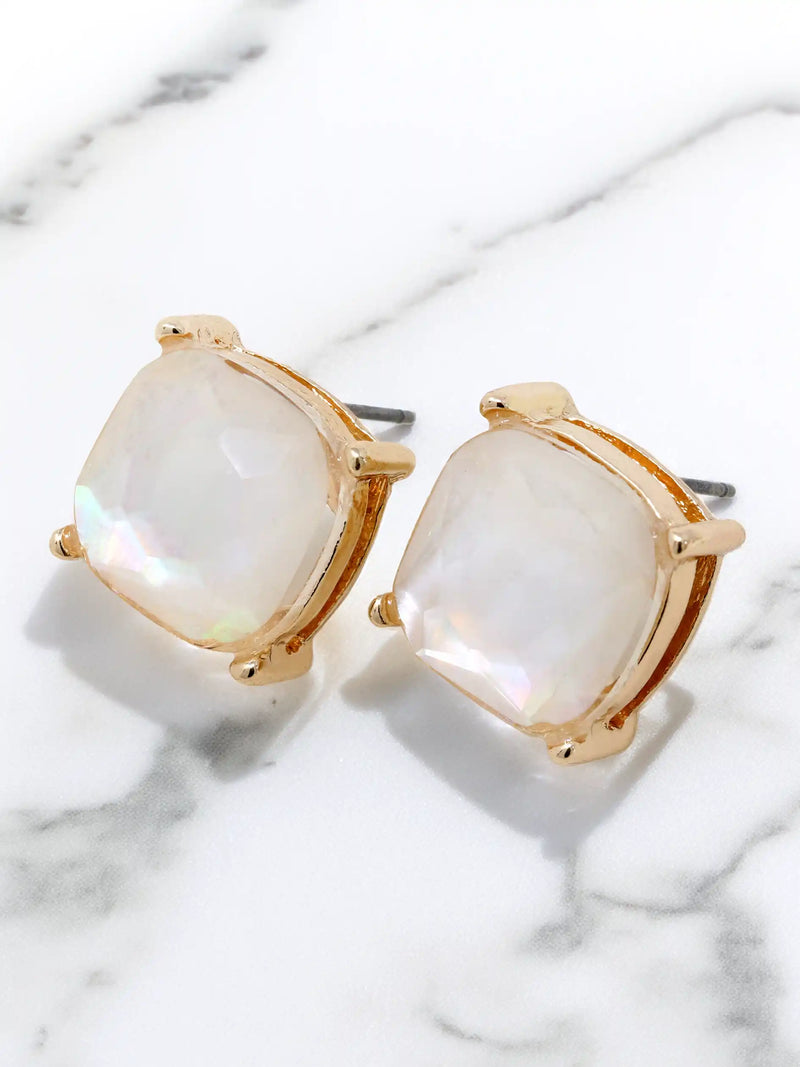 Gold-framed earrings with white stones on a marble surface
