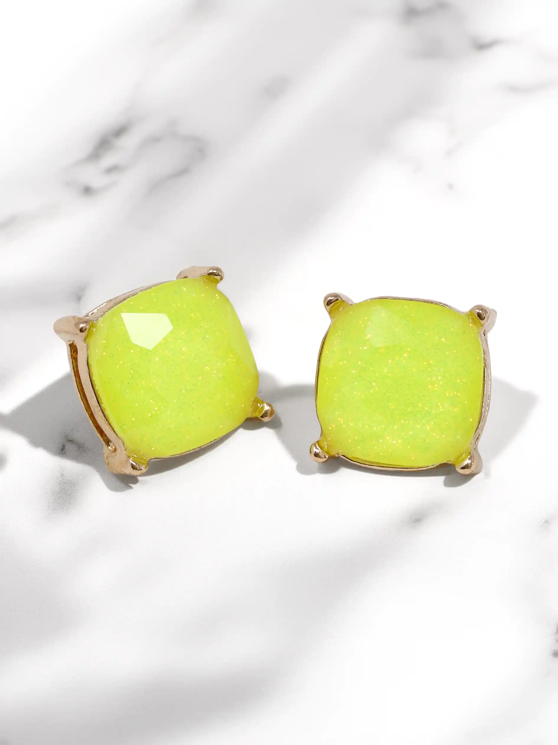 Pair of neon green earrings on a light marble background