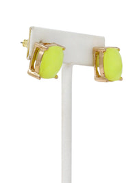 Neon green earrings with gold accents on a white stand