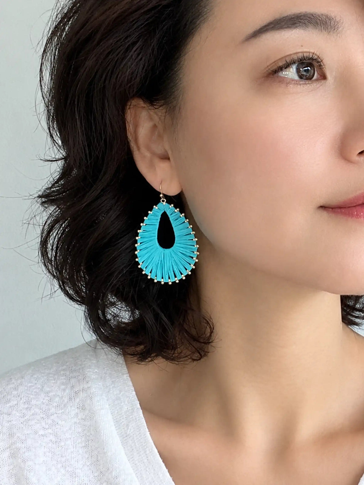 Colorful woven natural raffia teardrop drop earrings in turquoise, white and hot pink with gold-plated brass metal.