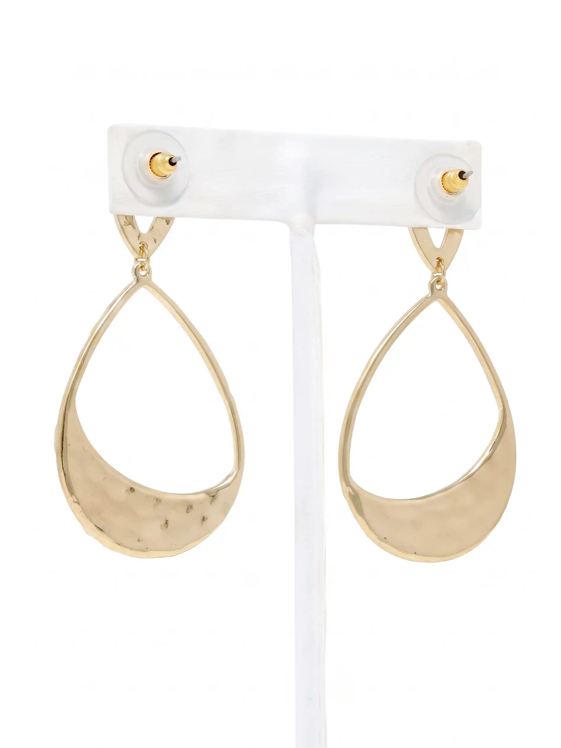 A pair of gold teardrop-shaped drop earrings with a hammered texture on the lower half, displayed on a white plastic jewelry stand against a white background.
