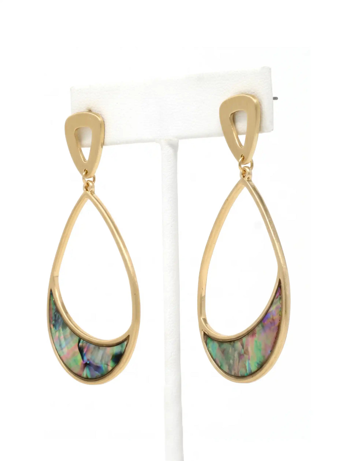 A pair of gold teardrop dangle earrings with a curved iridescent abalone shell inlay, displayed on a white jewelry stand against a white background.