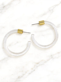 Pair of clear Lucite hoop earrings by Bauble Sky featuring polished transparent resin, gold-tone accents, and a modern minimalist design.