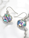 Shell-shaped earrings with colorful interior on a marble surface
