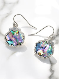 Shell-shaped earrings with colorful interior on a marble surface