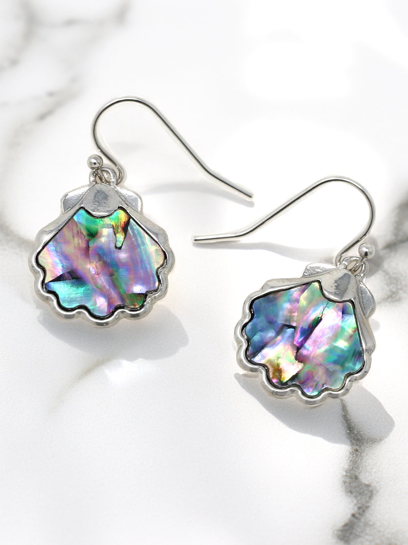 Shell-shaped earrings with colorful interior on a marble surface