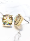 Gold earrings with colorful gemstones on a marble surface