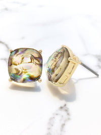 Gold earrings with colorful gemstones on a marble surface
