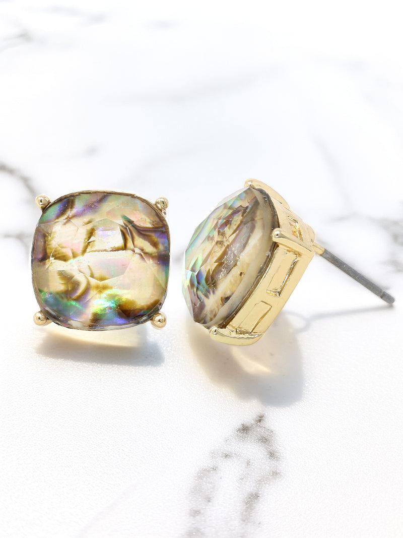 Gold earrings with colorful gemstones on a marble surface