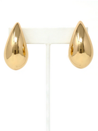 A pair of polished gold teardrop-shaped stud earrings displayed on a white T-shaped jewelry stand against a white background.