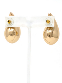 A pair of gold teardrop-shaped stud earrings displayed on a white plastic jewelry stand against a white background.