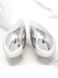 A pair of polished silver teardrop-shaped wall art pieces with a highly reflective metallic finish, displayed on a white marble surface.