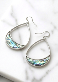 Silver earrings with abalone shell inlay on a marble surface