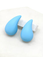 A close-up of light blue puffy hollow teardrop earrings, showcasing their modern and minimalist design. The earrings make a statement with their sleek metal construction and distinctive shape.