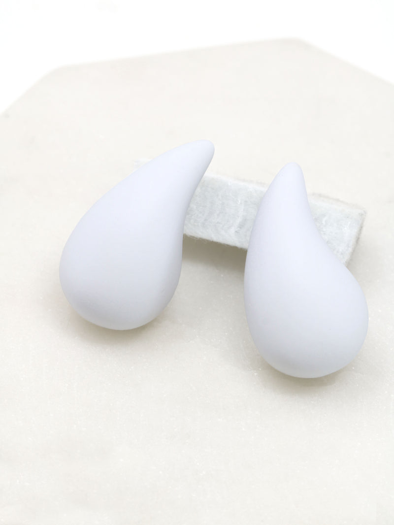A close-up of white puffy hollow teardrop earrings, showcasing their modern and minimalist design. The earrings make a statement with their sleek metal construction and distinctive shape.