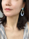 A pair of two-tone oval resin drop earrings with aqua blue studs and cream and glittery light blue oval dangles.