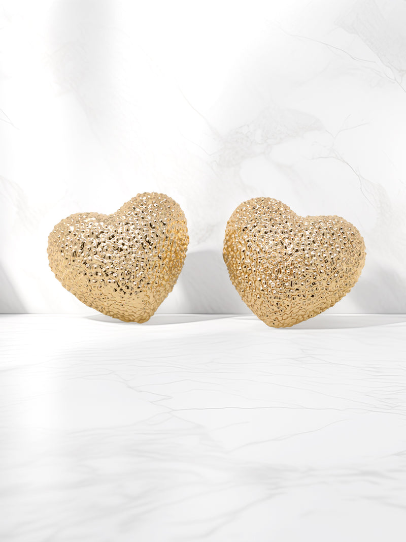 A pair of gold-tone textured puffy heart stud earrings with a delicate, intricate surface pattern.
