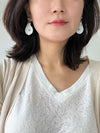 A pair of white natural shell drop earrings featuring turquoise accent stones and gold floral studs.
