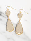 Beige and gold earrings on a marble surface