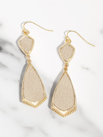 Beige and gold earrings on a marble surface