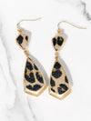 Leopard print earrings with gold accents on a marble background