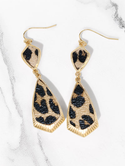 Leopard print earrings with gold accents on a marble background