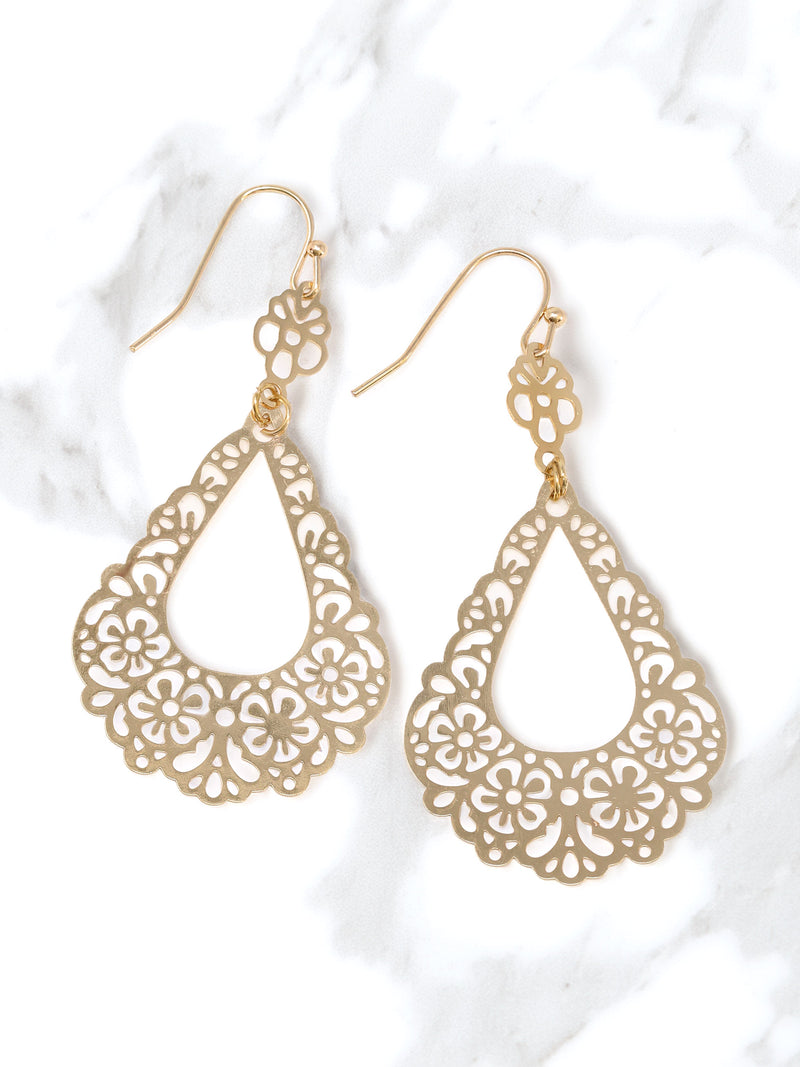Gold filigree earrings on a white marble background