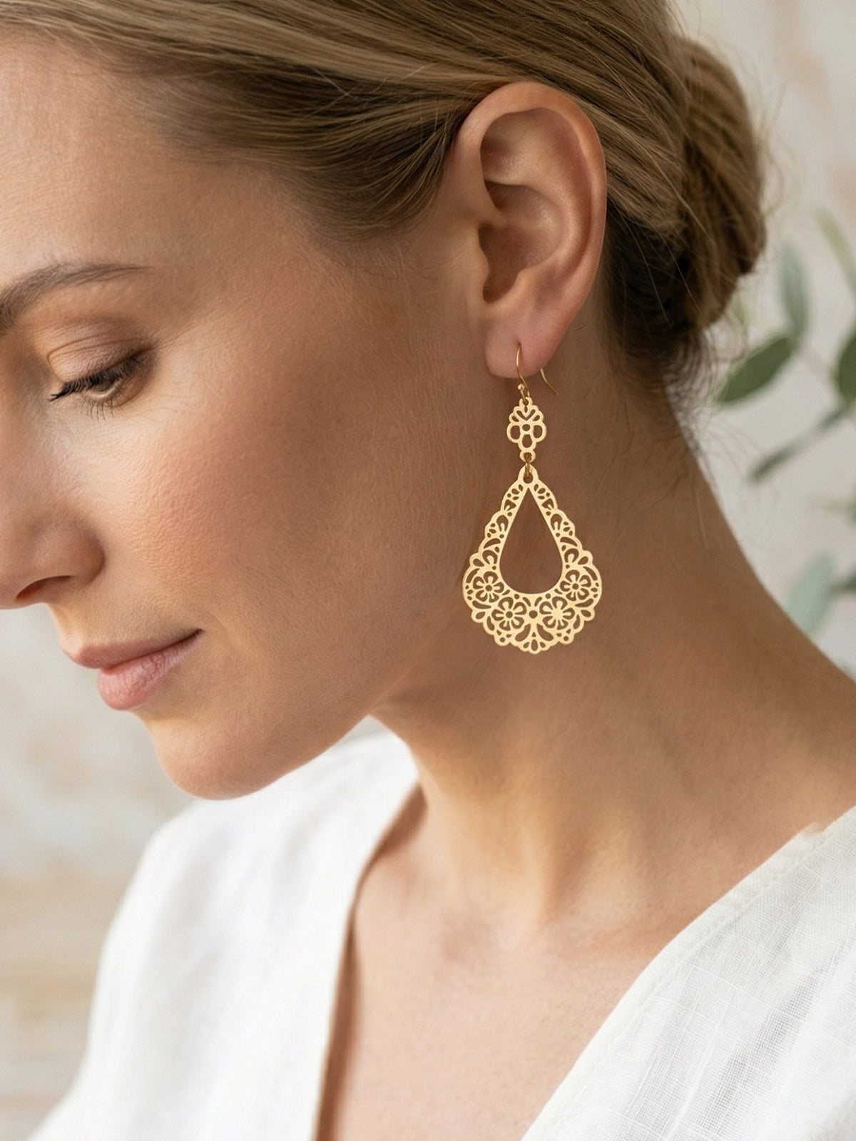 Close-up of a woman wearing gold earrings with a blurred background