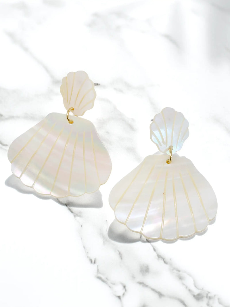 Shell-shaped earrings on a marble surface