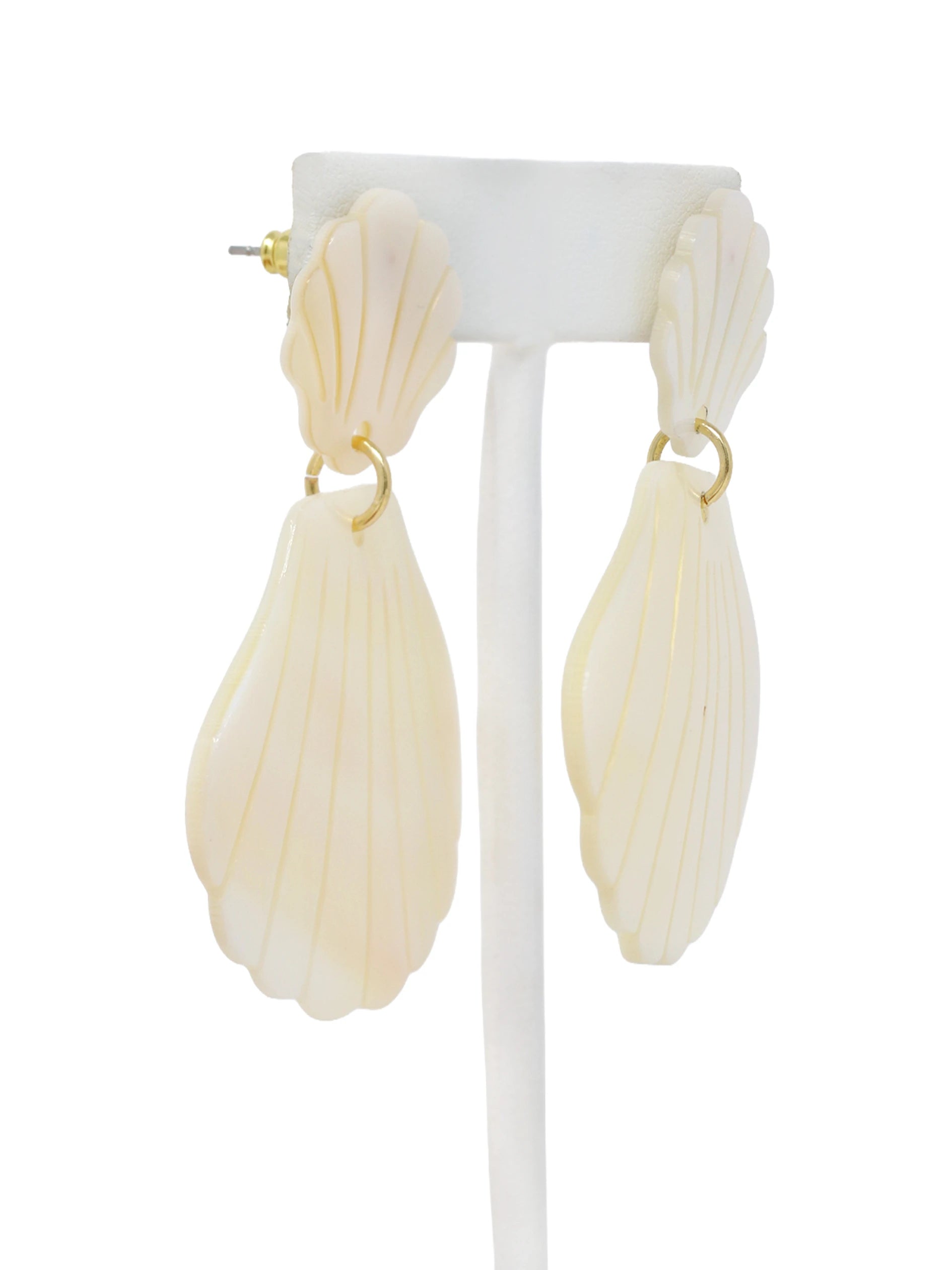 Shell-shaped earrings on a white stand with a white background