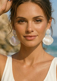 Woman wearing shell earrings with a beach background