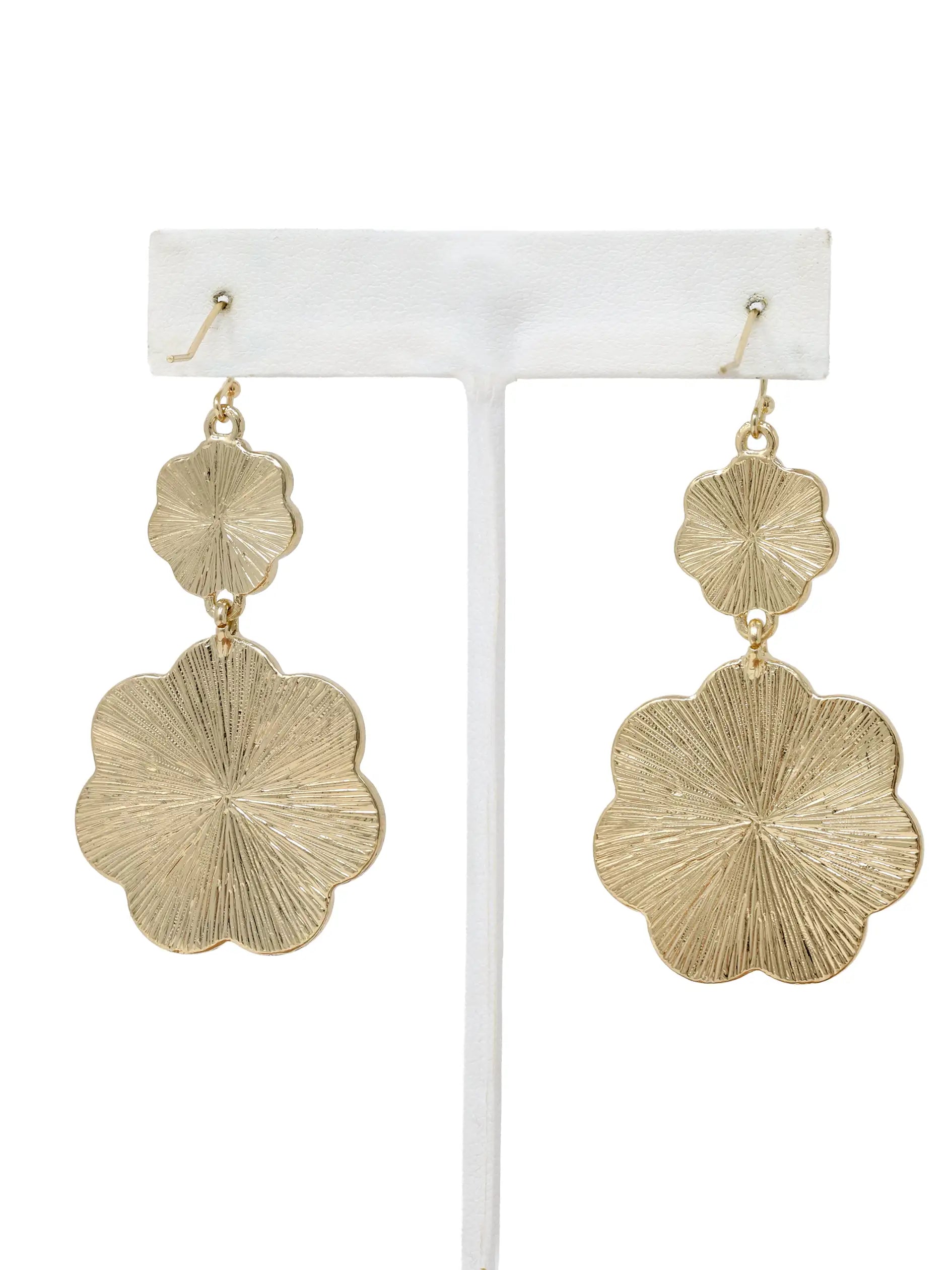 Gold floral earrings on a white display stand