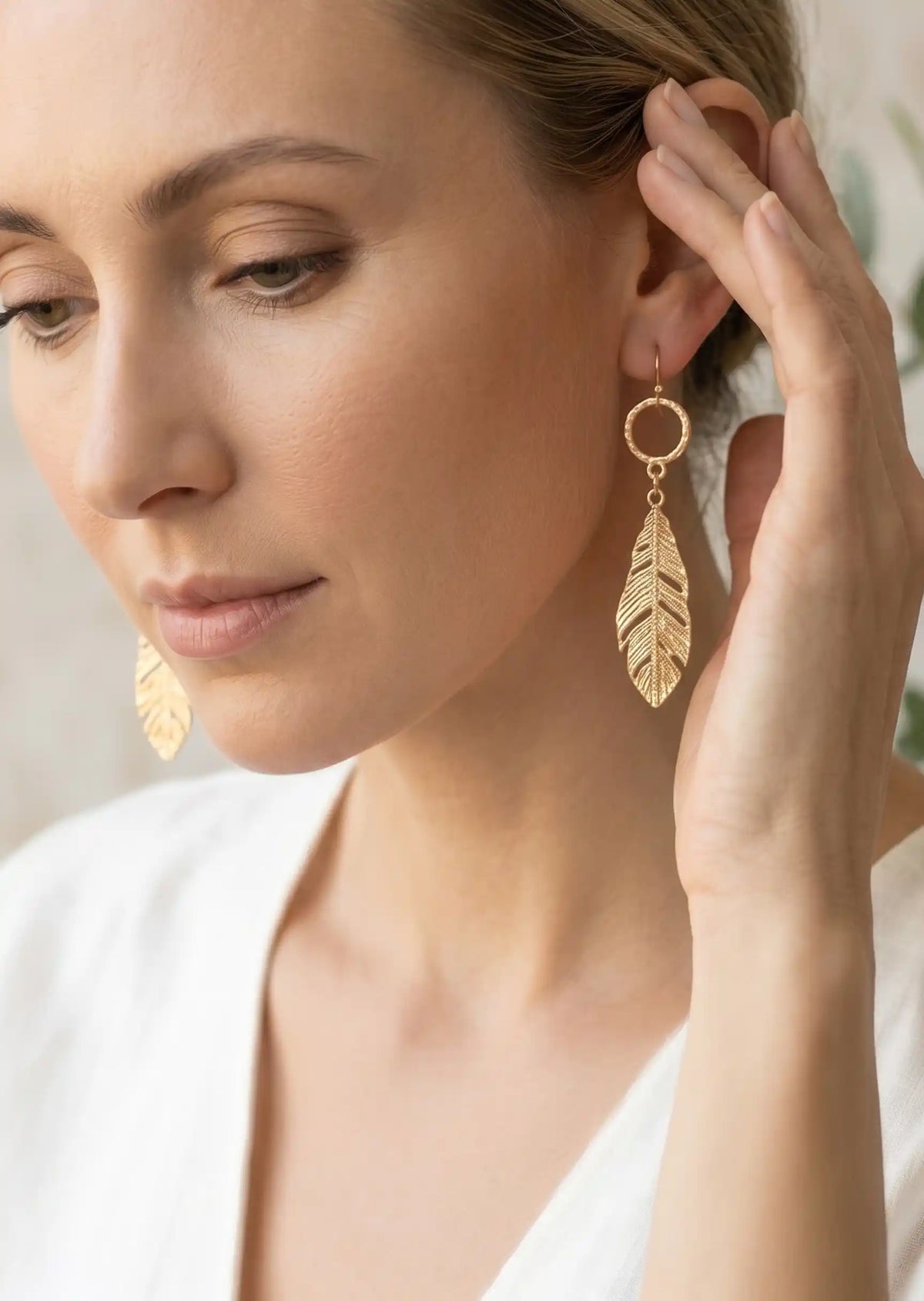 Gold leaf drop dangle earrings with textured circular links and detailed cutout leaf pendants.
