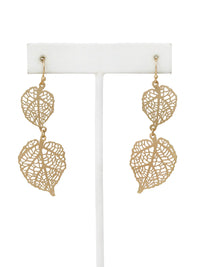 Gold leaf-shaped earrings on a white stand against a white background
