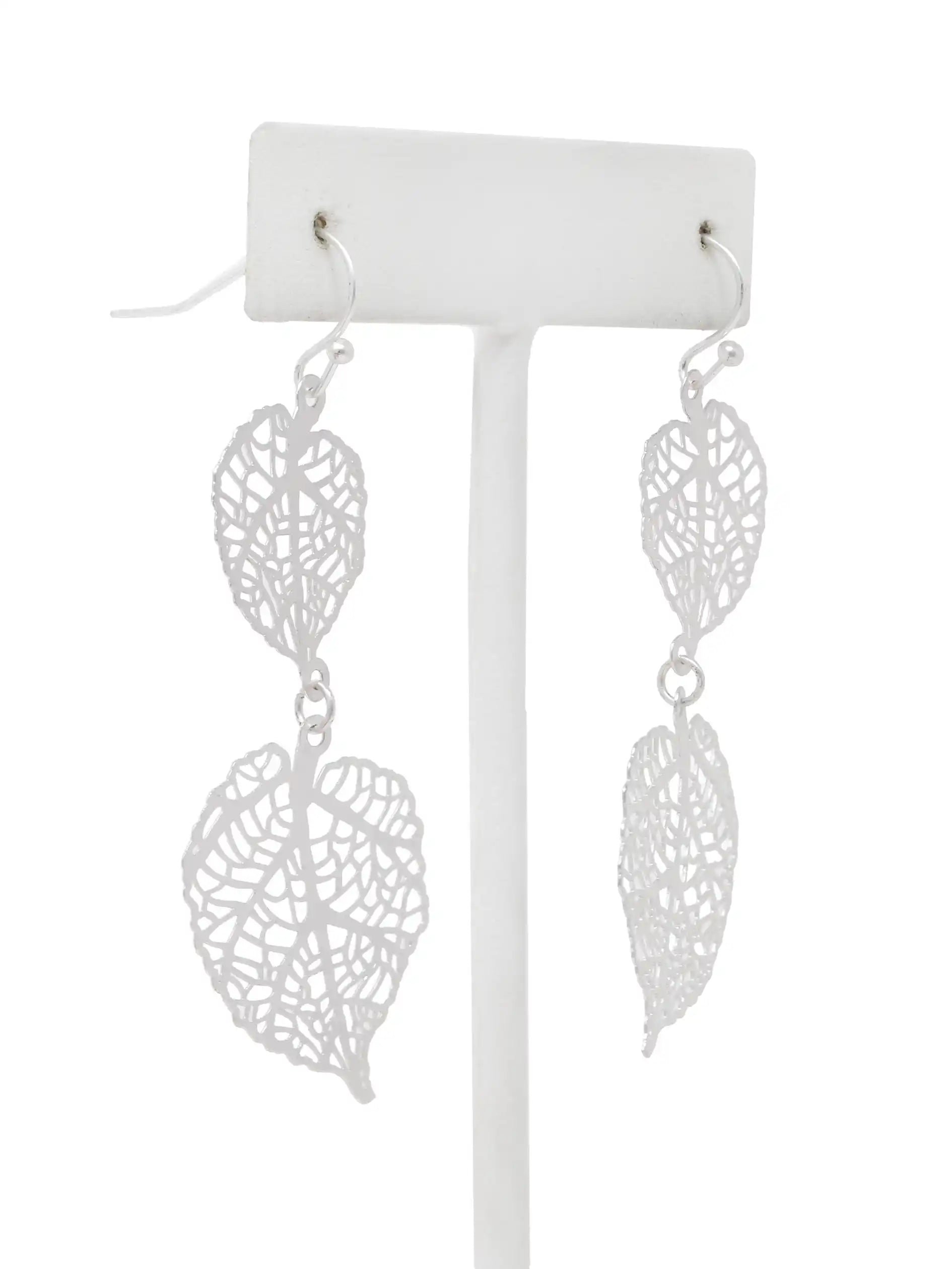 Silver leaf-shaped earrings on a white stand against a white background