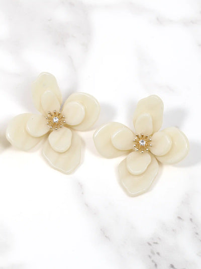 Cream-colored flower-shaped earrings on a marble surface