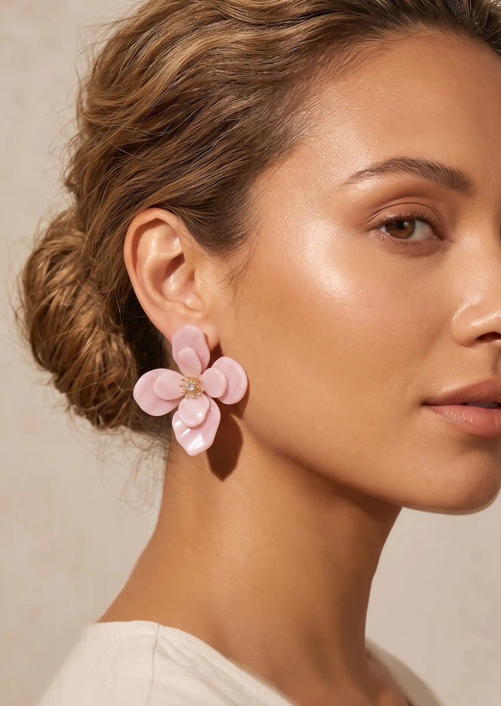 Close-up of a woman wearing pink floral earrings with a neutral background