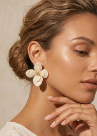 Close-up of a woman wearing a floral earring with a neutral background