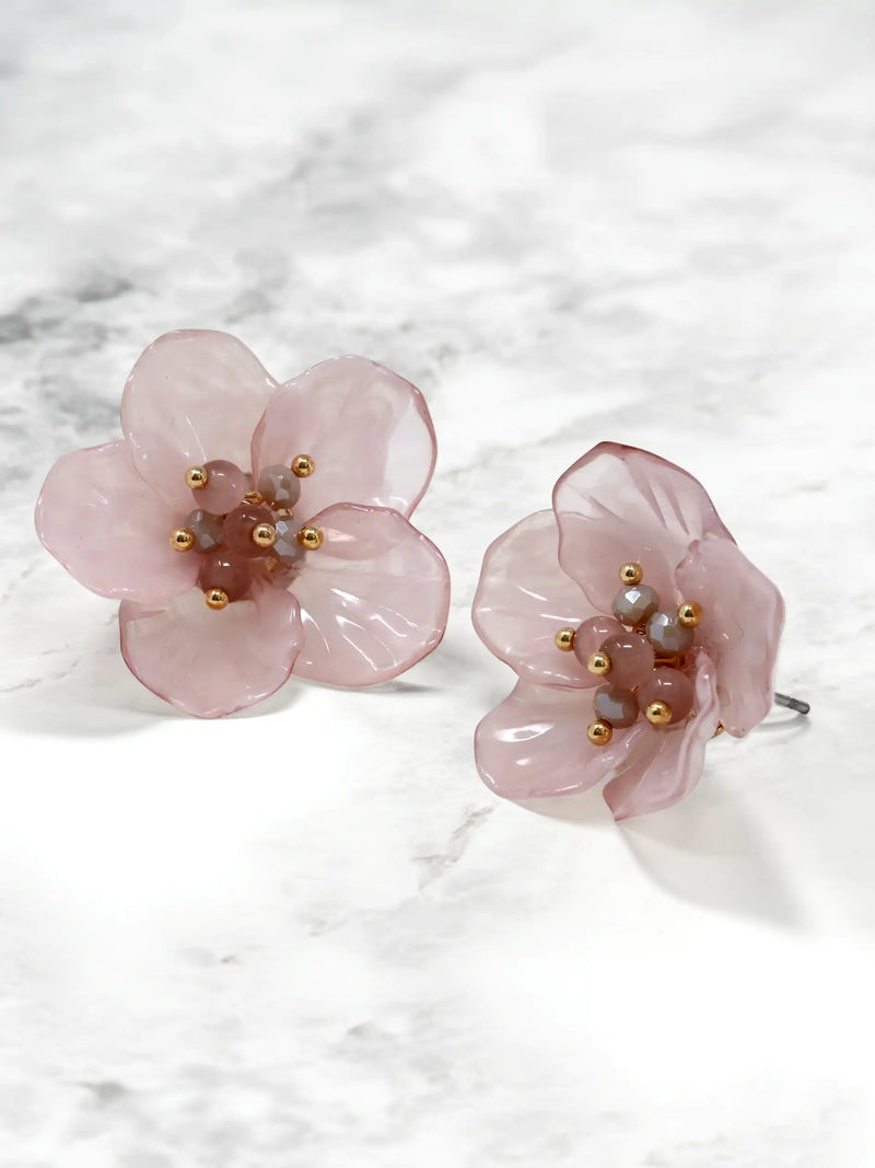 Pink floral earrings with gold accents on a white marble background