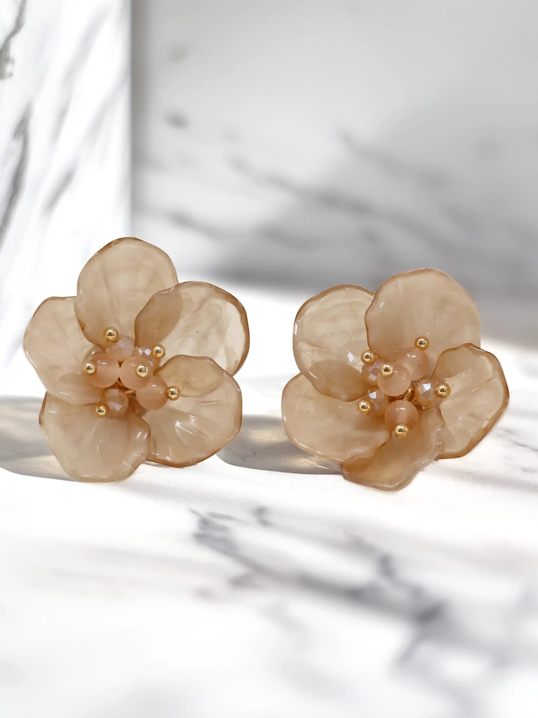Pair of beige floral earrings on a light background