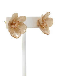 Pair of beige floral earrings on a white stand against a white background