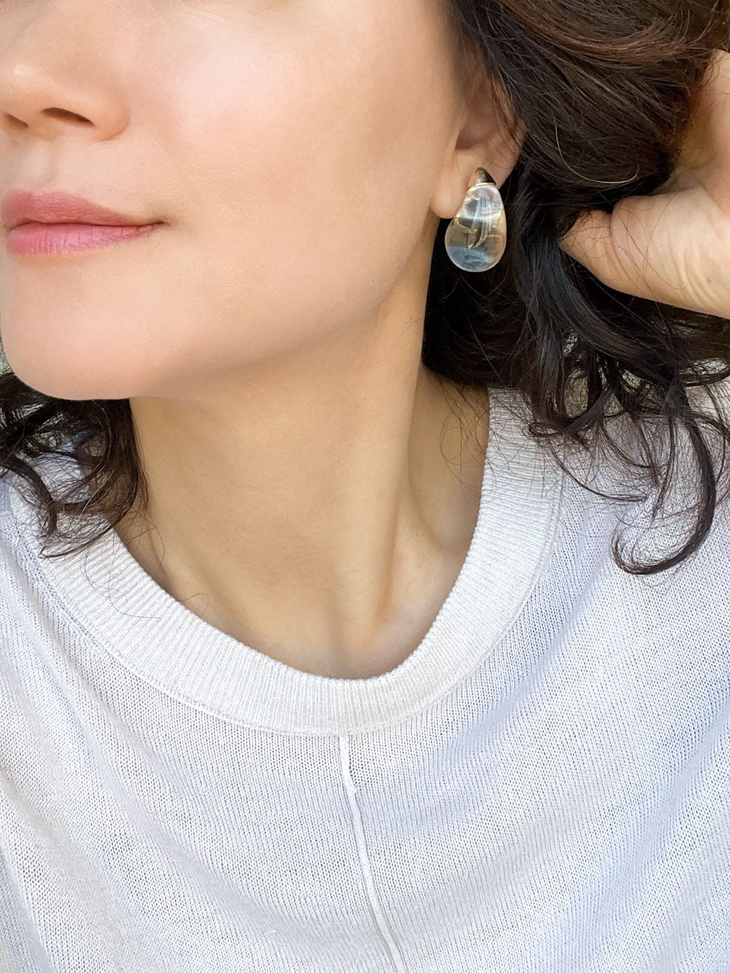 A pair of clear resin teardrop-shaped stud earrings with gold-toned caps, showcasing their smooth, glossy finish and minimalist design.