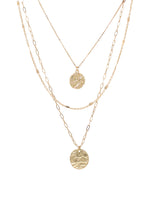 This simple yet stylish necklace in gold consists of three layers of metallic chains, adorned with dangling charms. The chains include a fine cable chain, a textured chain, and a paperclip chain, giving the necklace a modern and versatile look.