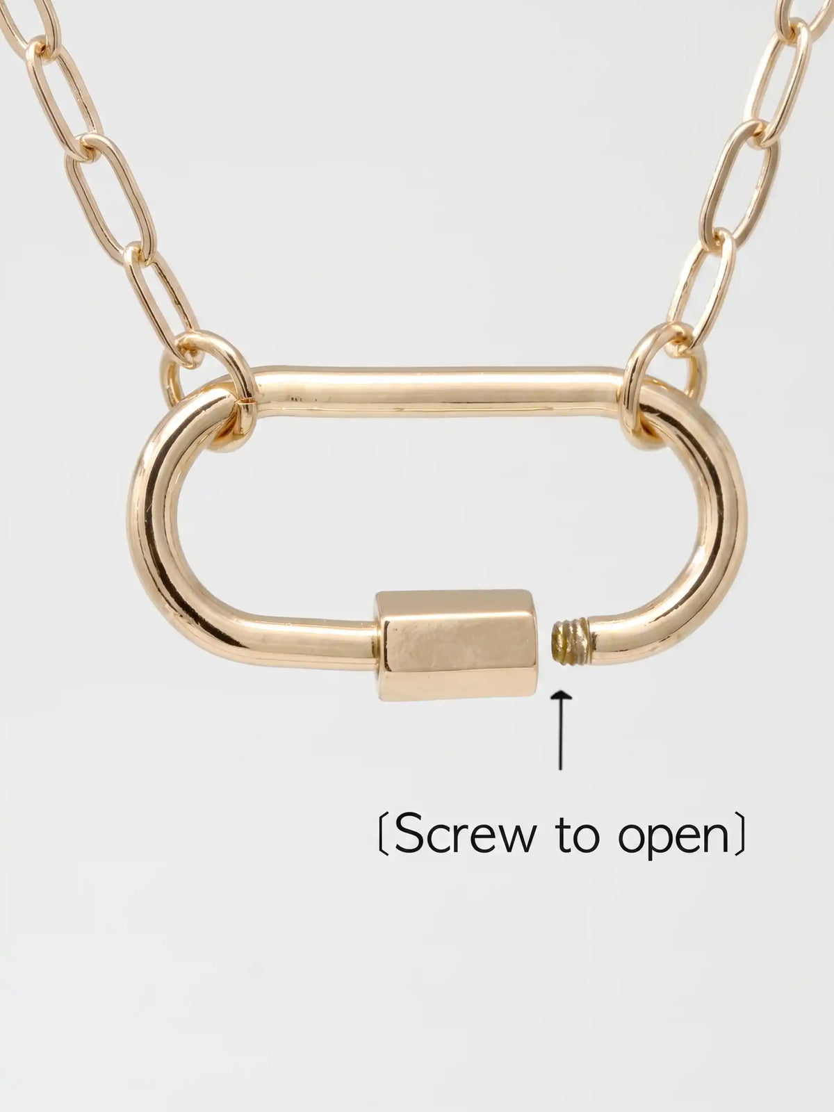 Gold-toned metal necklace with a chain and an open-link carabiner featuring a rectangular clasp and a small screw detail, shown on a light gray background with the text '(Screw to open)' and an arrow pointing to the screw.